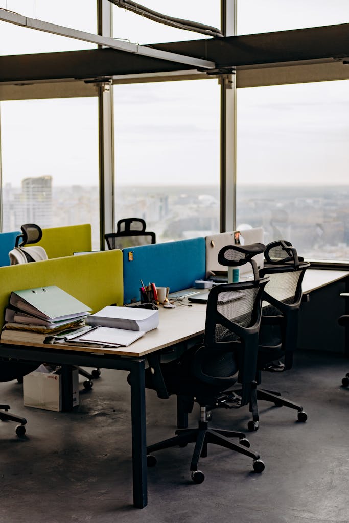 Open office space with colorful dividers and a city view, typifying modern urban work environments.
